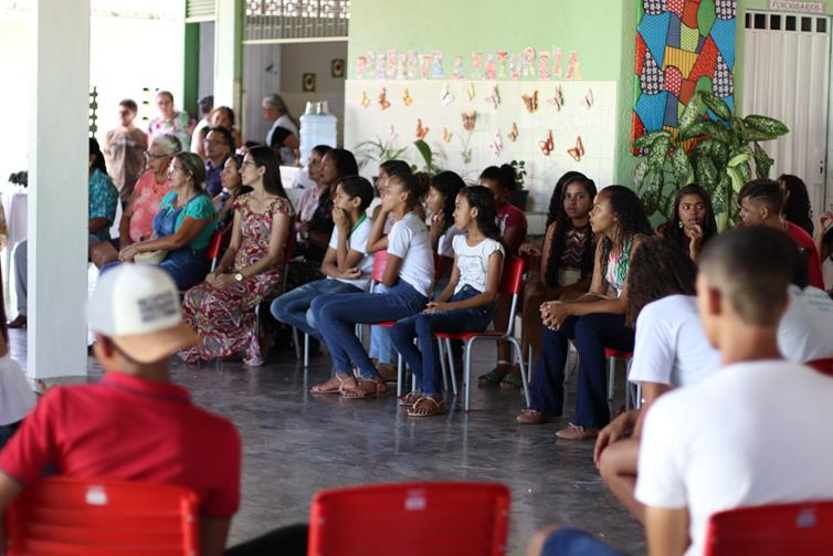 Estudantes sentados em cadeiras no pátio da escola, assistindo à palestra