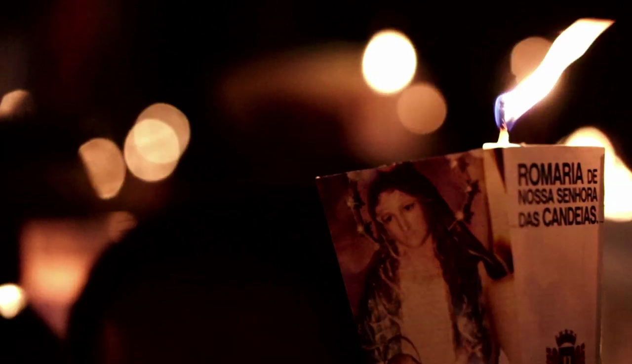 Folheto com imagem de Nossa Senhora das Candeias, com vela atrás, e imagens de velas desfocadas